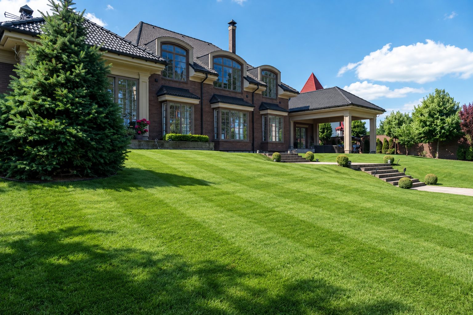 Freshly mowed striped lawn with a mower in the distance